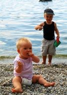 children on pebbles near the water