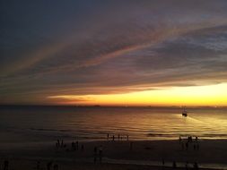 golden glow in sky beneath dark clouds above sea