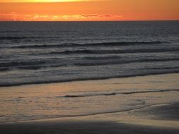 orange sunset over ninety mile beach in New Zealand