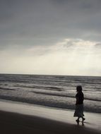 woman is walking along the coast at dusk