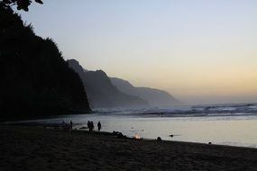 people on the beach in hawaii at dusk