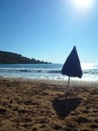 folded beach umbrella on an empty beach