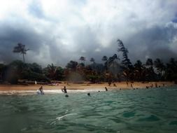 landscape of people bathe in the sea during a storm