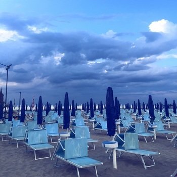 sun beds and umbrellas on the beach under a rainy sky