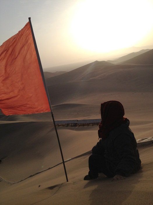 man and red flag in the desert