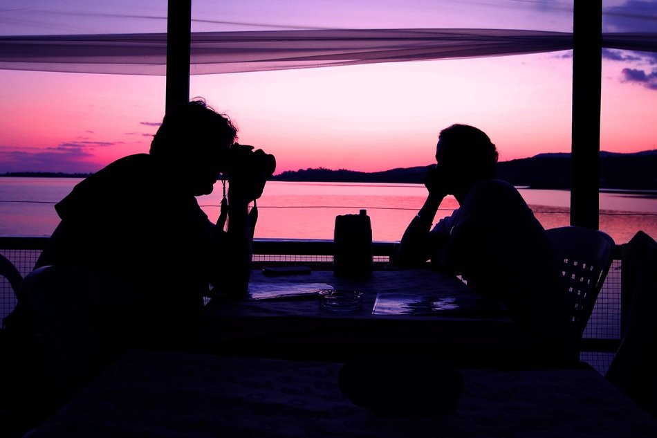 silhouettes of people at a table in a cafe at sunset