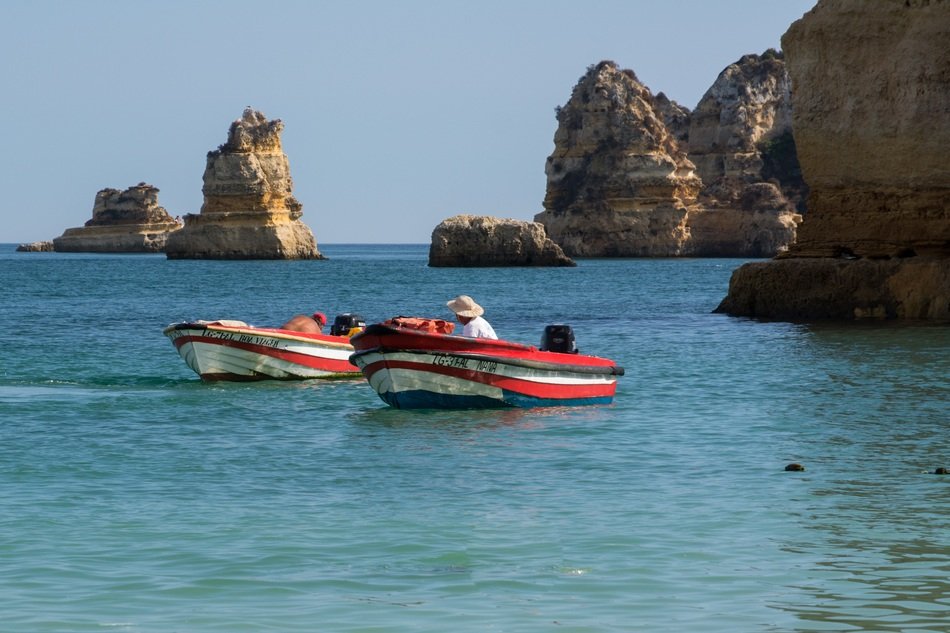 fishermen in boats in the ocean near the rocks