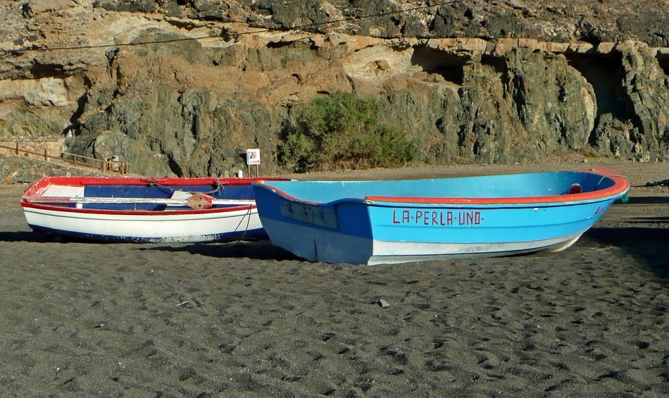 two fishing boats in the sand on the beach