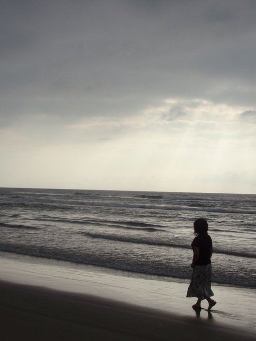 woman is walking along the coast at dusk