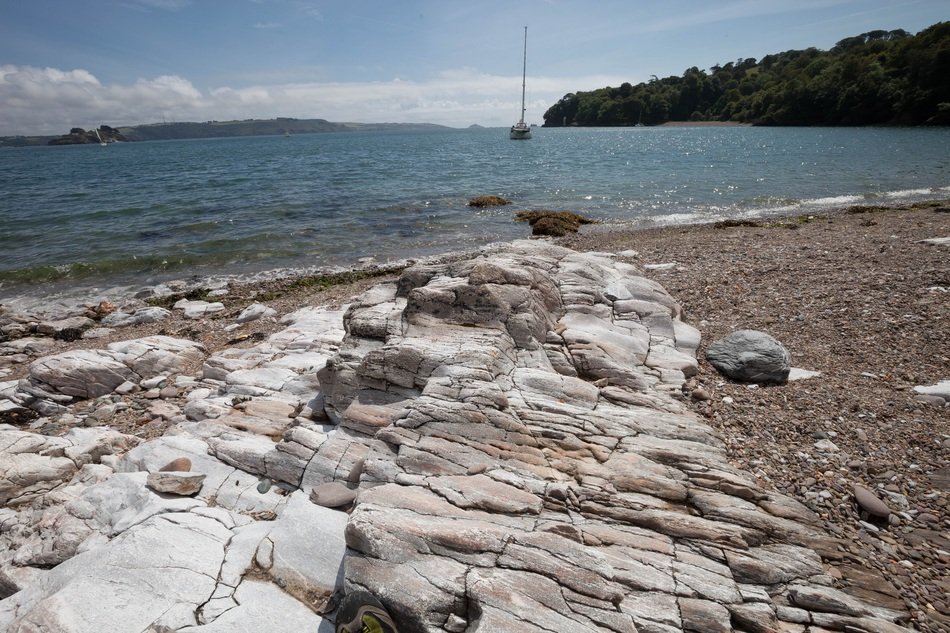 sailboat on the water on the background of the beach with stones