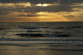 the sun behind the clouds over the sea at dusk