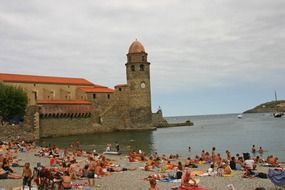 bell tower near the beach with vacationers in collioure