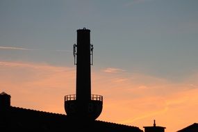 black silhouette of a large chimney at sunset