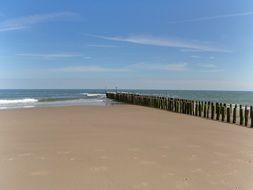 wooden breakwater on the sandy coast on a clear sunny day