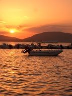 boat off the coast of Sardinia at colorful sunset, Italy