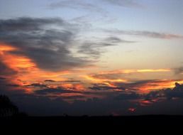bright red sunset glow and dark clouds at evening sky