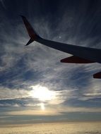 silhouette of the wing of the plane against a cloud