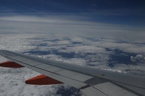 airplane wing above the clouds in the sky