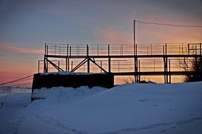 snow-covered bridge in the rays of sunset