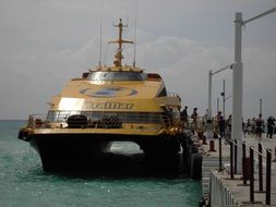 big yellow catamaran near the wooden pier