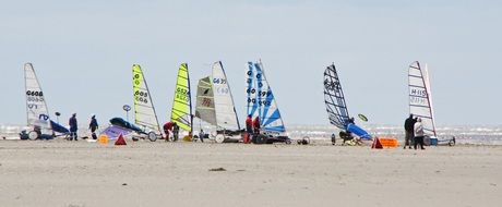 people at land sailing yachts on beach, germany, saint peter ording