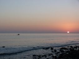 distant view of a boat at red sunset