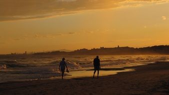 landscape of people walk along the beach at dusk