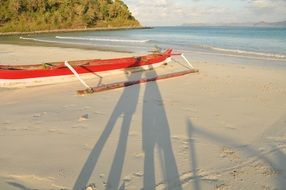 red boat and shadows of people on the beach