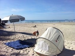 tent, towel and beach umbrella on the ocean