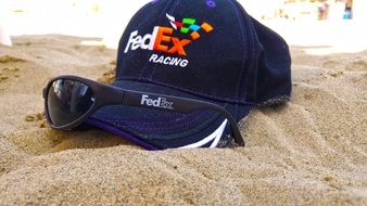 fedex hat and sunglasses on the beach sand close up
