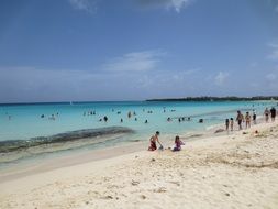 people sit on a sandy beach near the sea
