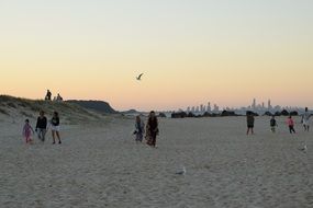 People walking along sand beach in the evening