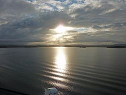 sun through the clouds reflected in the sea