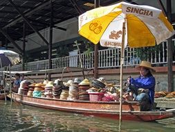 man on boat at floating market in thailand