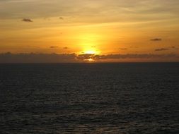 view of the sunset behind the clouds on the horizon