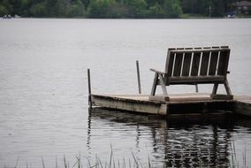 wooden bench on pier at calm water