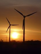 two windmills against an orange sunset