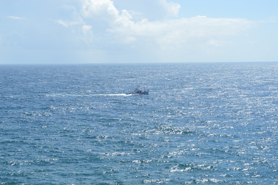 boat fishing on gleaming sea surface