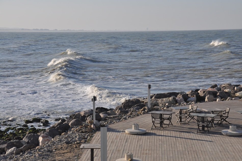 tables and chairs on pebble beach at sea