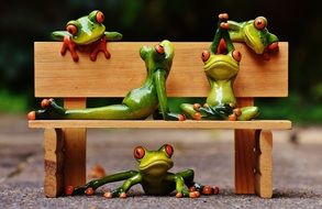 group of toy Frogs in Yoga poses on Bench