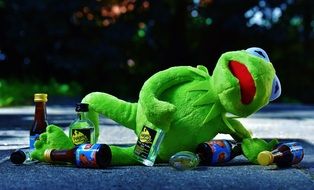 green frog sitting on the floor with a bottle in his hand