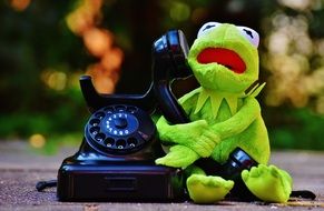 figure of a green frog with a black phone