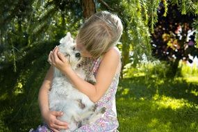 portrait of little girl holding a white dog