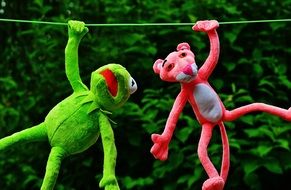 green frog hanging on a rope near the pink panther
