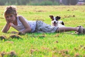 boy and puppy are resting on the field