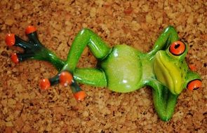 ceramic green frog lays on the sand