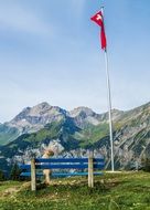 flag of switzerland near a bench on a mountain