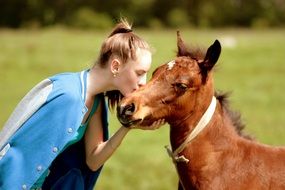 portrait of girl is kissing pony on the cheek
