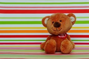 brown teddy bear on a background of colored bands