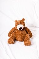 brown teddy bear on white cloth